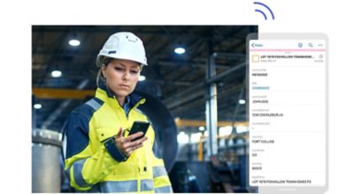 A person in a white hard hat and yellow safety jacket looking at a mobile phone held in their hand, beside a large graphic of a phone screen displaying a fictional person's account data