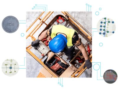 An aerial view of a field worker in a blue hard hat, standing on a hydraulic lift to work on powerlines